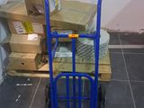 un diable bleu chargé de cartons dans une pièce
