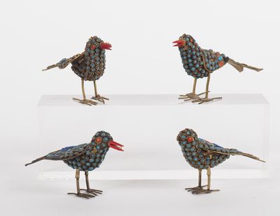 three small metal birds sitting on top of a clear shelf