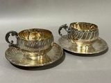 pair of silver plated tea cups and saucers on saucers