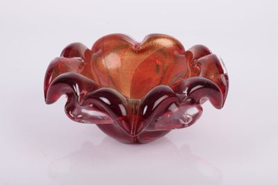 a red glass bowl that is sitting on a white surface