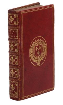 un vieux livre rouge aux tranches dorées, orné d'un blason sur la couverture