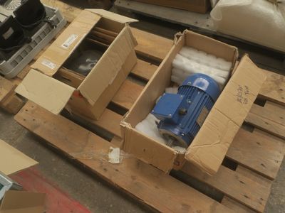 une boîte contenant une pompe bleue, posée sur une palette
