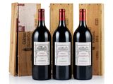 three bottles of red wine sit in front of a wooden box