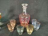 several glasses and a decanter on a table with a black background