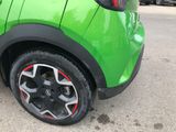 a green car with red rims parked in a parking lot