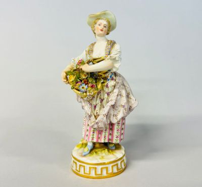 an antique porcelain figurine of a woman holding a basket of flowers