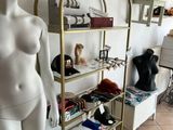 a female mannequin standing next to a shelf with a hat on it