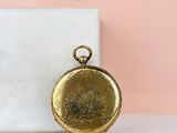 an image of a gold pocket watch sitting on top of a marble block