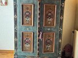 une armoire verte décorée de tableaux, placée dans un coin de la pièce