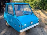une petite voiture bleue garée devant un garage