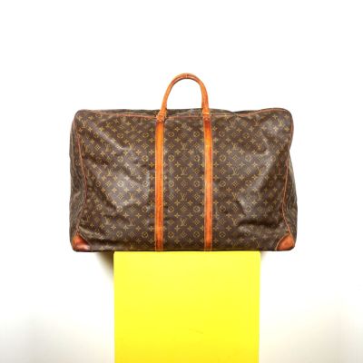 LOUIS VUITTON : Sac de voyage en toile Monogram sur fond mar…