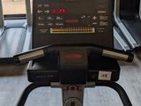 a tread machine in the gym with a view of the trees outside