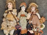 three antique dolls are lined up on a gray surface