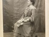 black and white photograph of a woman in a dress sitting on a chair