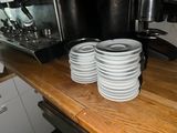 several white plates are stacked on a wooden counter in front of a coffee machine