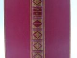an old book with a red cover sitting on top of a white table