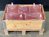 une caisse en bois remplie de bouteilles contenant un liquide rouge, posée sur une palette