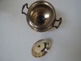a silver pot and a silver spoon on a white table