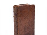 an old book is sitting on a white surface with a white background