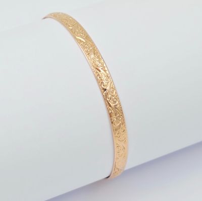 un gros plan d'un bracelet en or posé sur une serviette