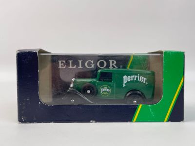 un petit camion vert dans une boîte, posé sur une surface blanche