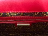 the inside of a red purse with a gold and black pattern