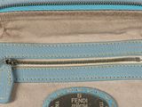 a close up of a blue and beige purse on a white surface