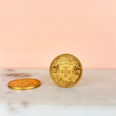 a gold coin sitting on top of a marble counter next to a gold coin