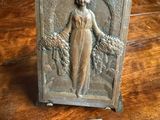 une photo d'une plaque posée sur une table, sur laquelle figure le portrait d'une femme