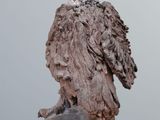 sculpture of an owl perched on a rock on a wooden table