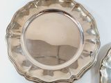 two silver plates on a white table with a mirror
