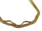 gros plan d'un collier en or sur fond blanc