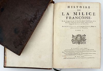 un vieux livre ouvert posé sur une table, à côté d'un autre livre