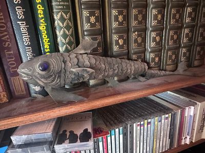 a fish statue on a book shelf in front of many books