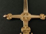 gold cross on a black surface with a black background