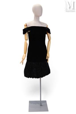 Le mannequin porte une robe noire ornée de volants.