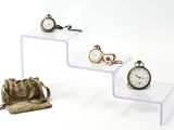 trois étagères en verre sur lesquelles sont posées des montres et un sac à main