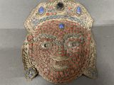 an old silver and red mask on display in a glass case