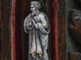 a statue of a man holding a rosary in a wooden frame