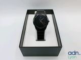 la montre se trouve dans un coffret noir posé sur une surface blanche