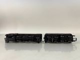 two black trains sitting side by side on a white surface