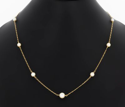a gold necklace with pearls on a mannequin neck