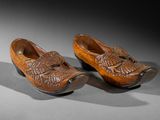 pair of carved wooden shoes with fish heads on them