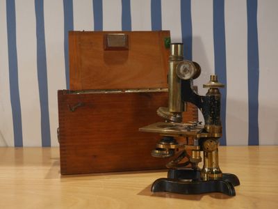 un microscope posé sur une table, avec une boîte à l'arrière-plan
