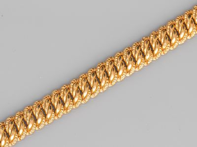 a close up of a gold bracelet on a gray surface