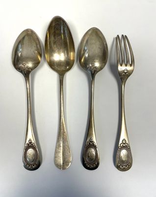 four silver spoons and a fork on a white surface