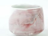 a white and pink cup sitting on a white surface
