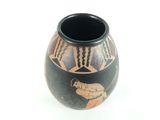 a black vase with a design on it on a white surface