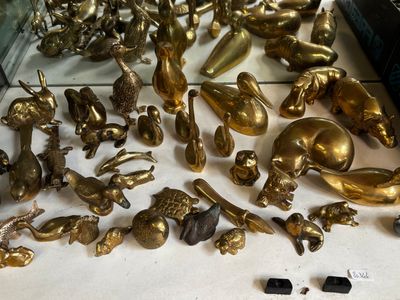 Des figurines en laiton sont exposées sur une table, dans une vitrine.