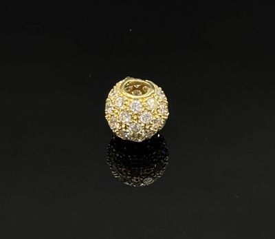 a gold and diamond bead on a black surface